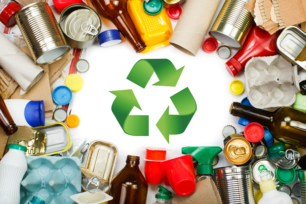 Green recycling logo surrounded by metal and plastic con tainers and waste on a white background